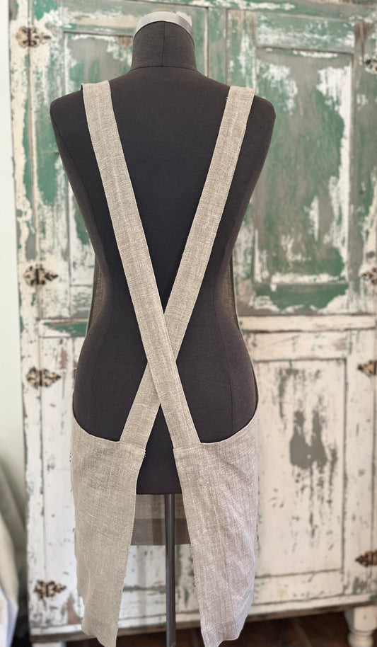 A dressmaker's Judy displays the back of the linen crossback apron with two pockets. A vintage green and white cabinet stands in the background.