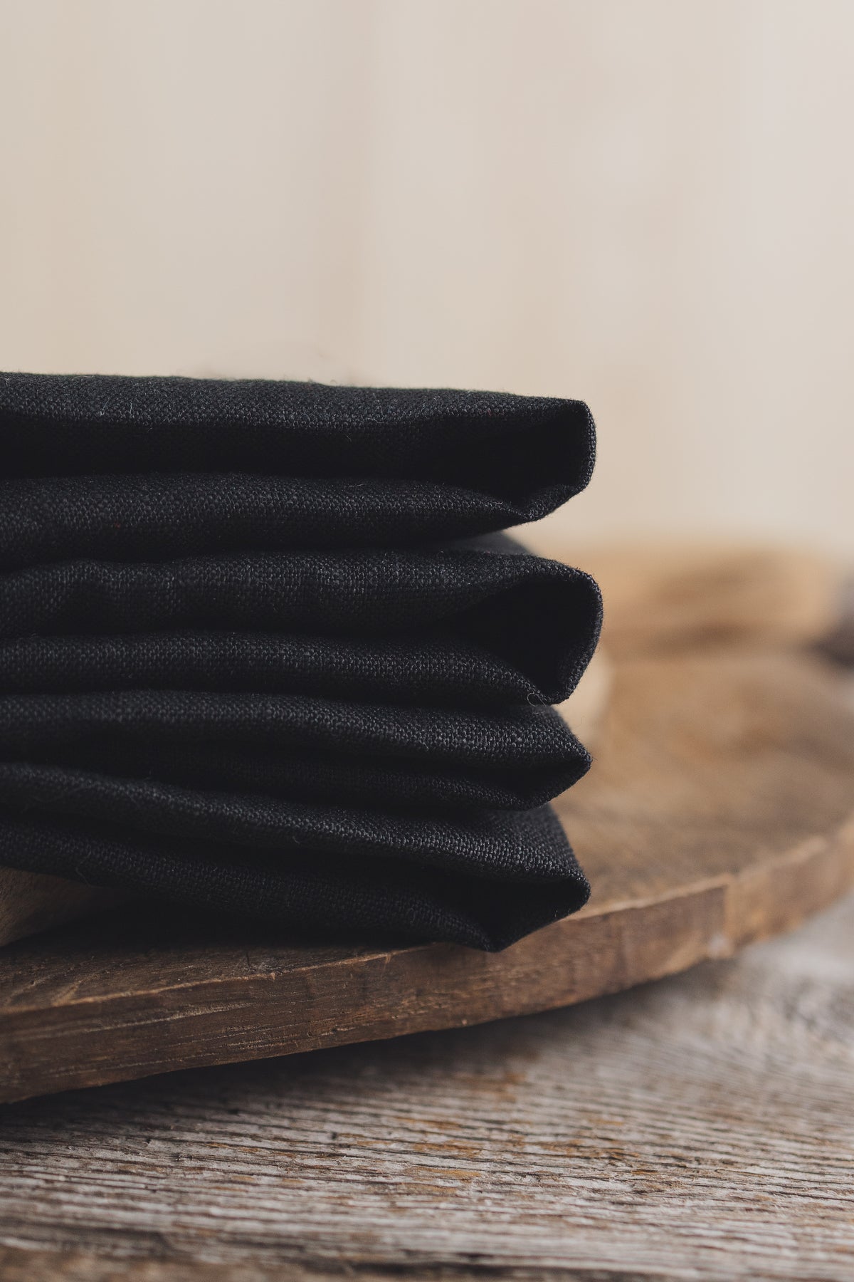 Stack of black fabric on a wooden surface with a neutral background