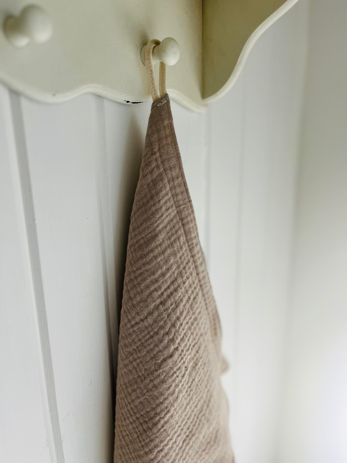 A close up of the hanging loop of the face cloth hanging from a peg.