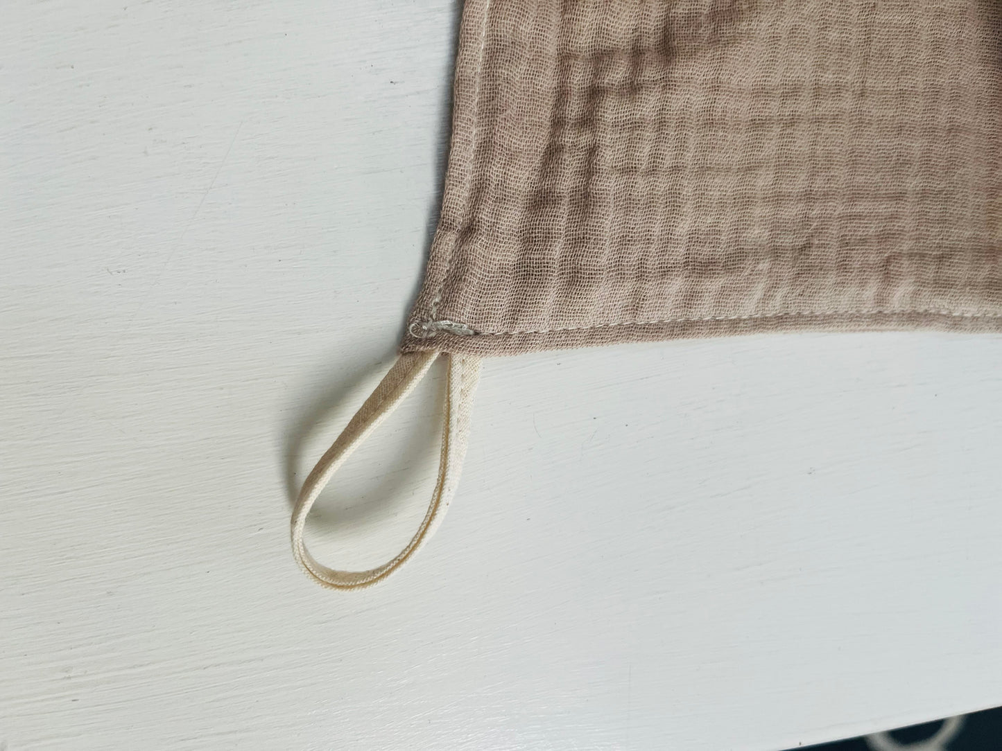 A loop of natural cotton muslin is sewn into the corner of the facecloth.