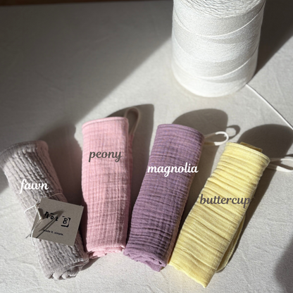 4 facial cleansing cloths are rolled up and laid alongside each other. Fawn is a light taupe. Peony is a soft pink. Magnolia is an earthy purple and Buttercup is a soft yellow. 