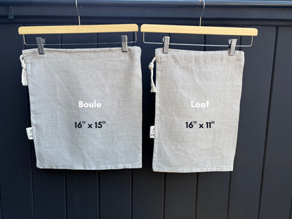 Two natrual linen bread bags are labeled 'Boule' and 'Loaf' with dimensions on a dark background.