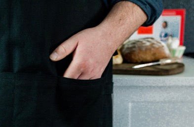 Detailed view of the 3-section front pocket holding a smartphone and tools, alongside dual integrated towel bars.