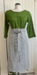 A dressmaker's Judy dressed in an apple-green dress sports and black and white striped half apron. The bow is tied in the front. She looks very elegant.