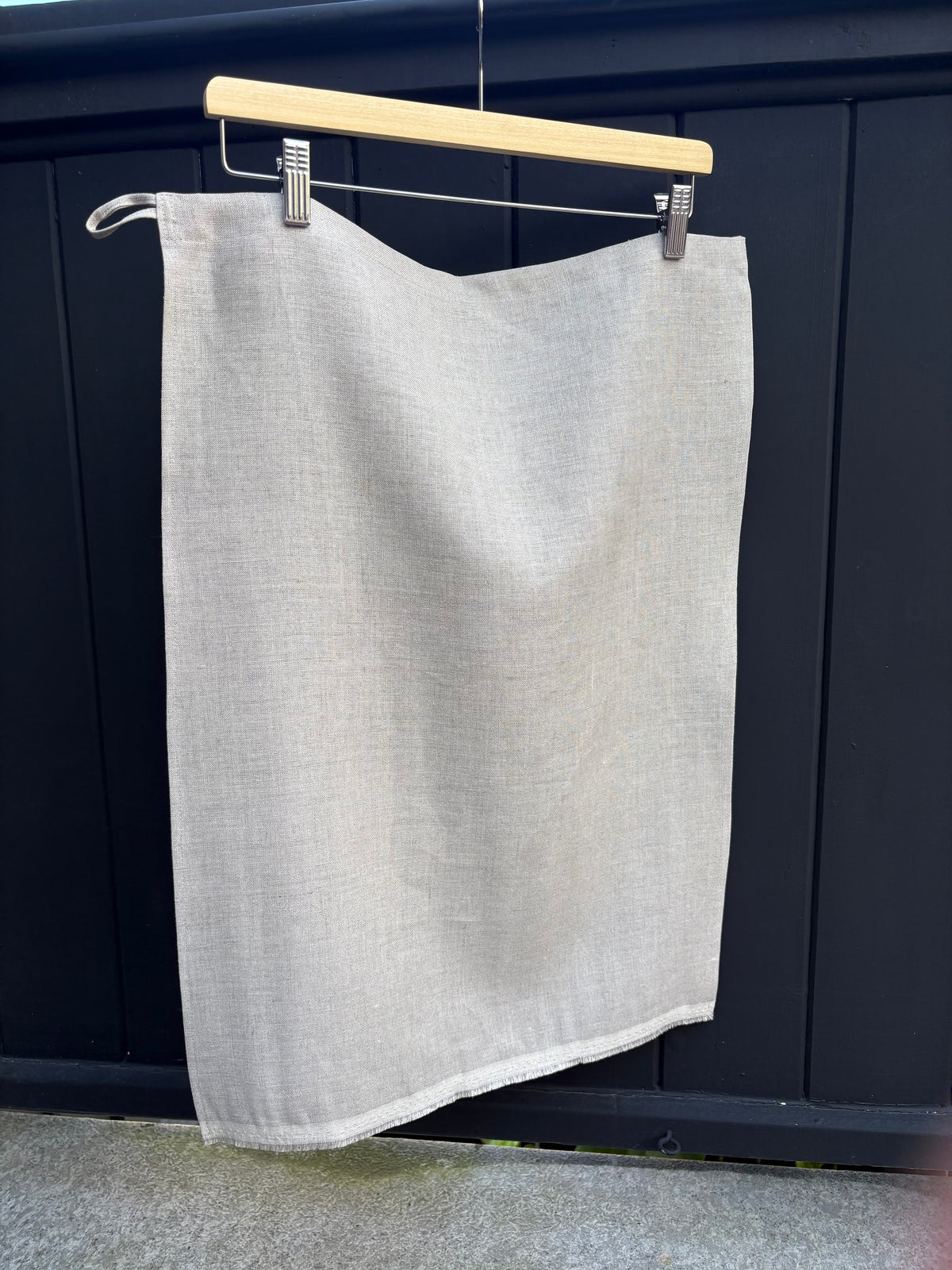 Natural tea towel hanging on a clothesline against a dark background