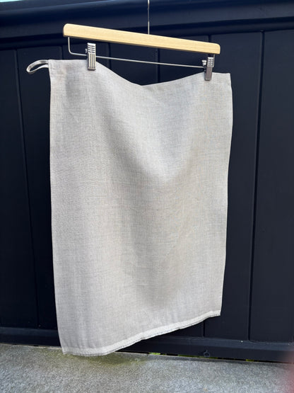 Natural tea towel hanging on a clothesline against a dark background