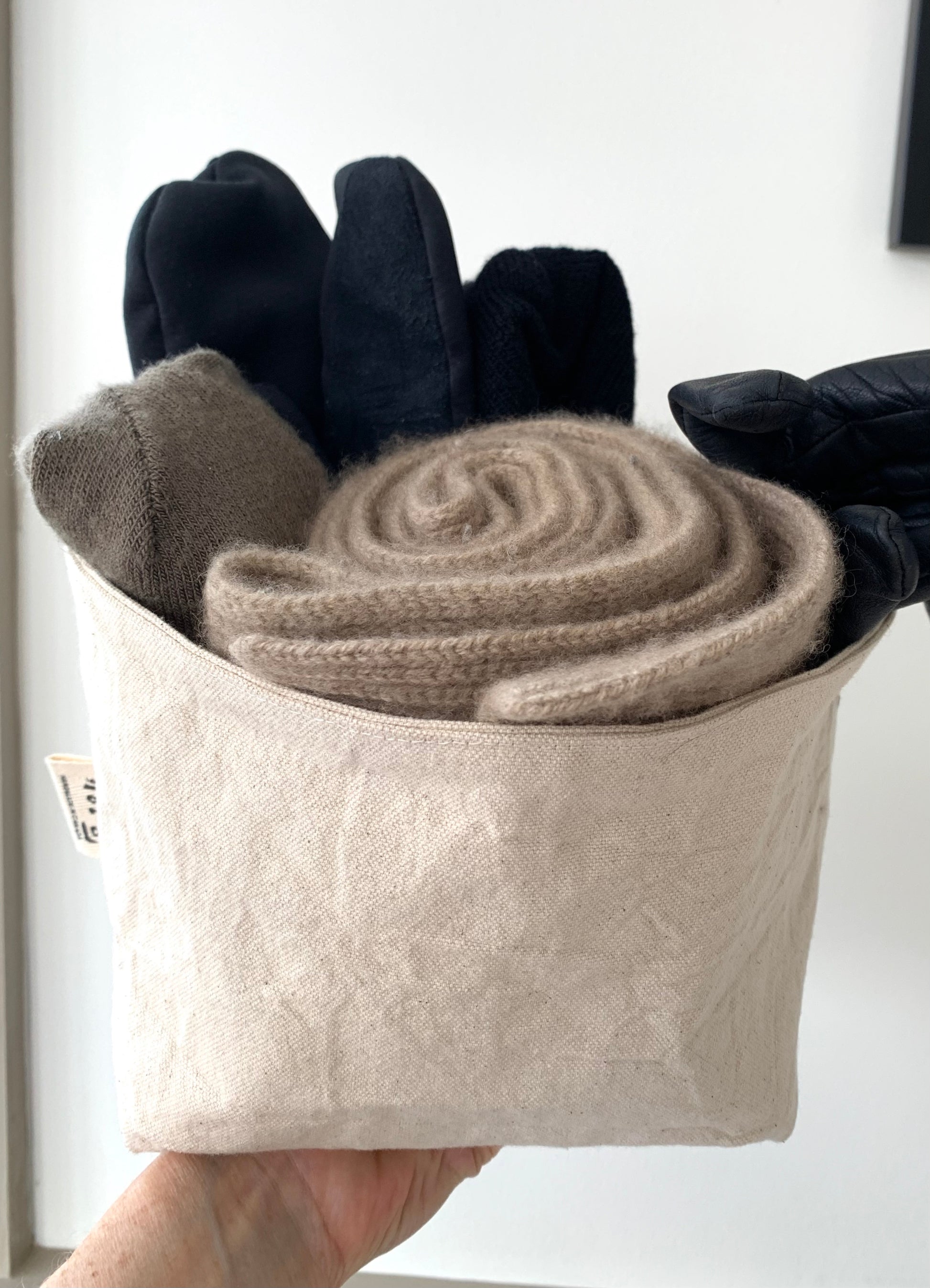 The large bucket filled with a rolled scarf, gloves and a hat