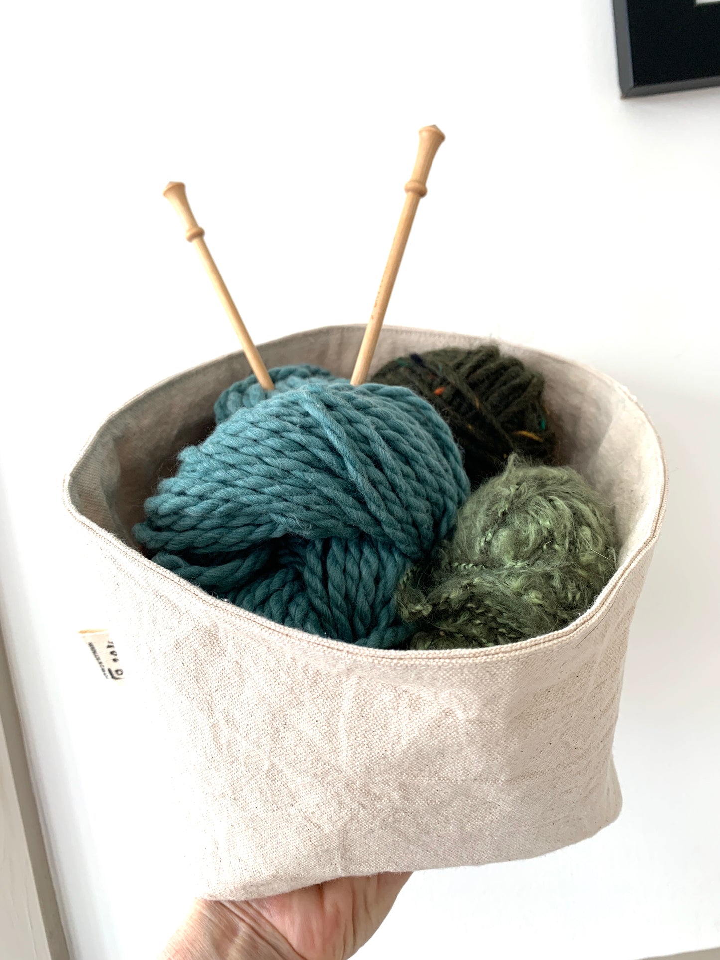 The large bucket filled with yarn and knitting needles