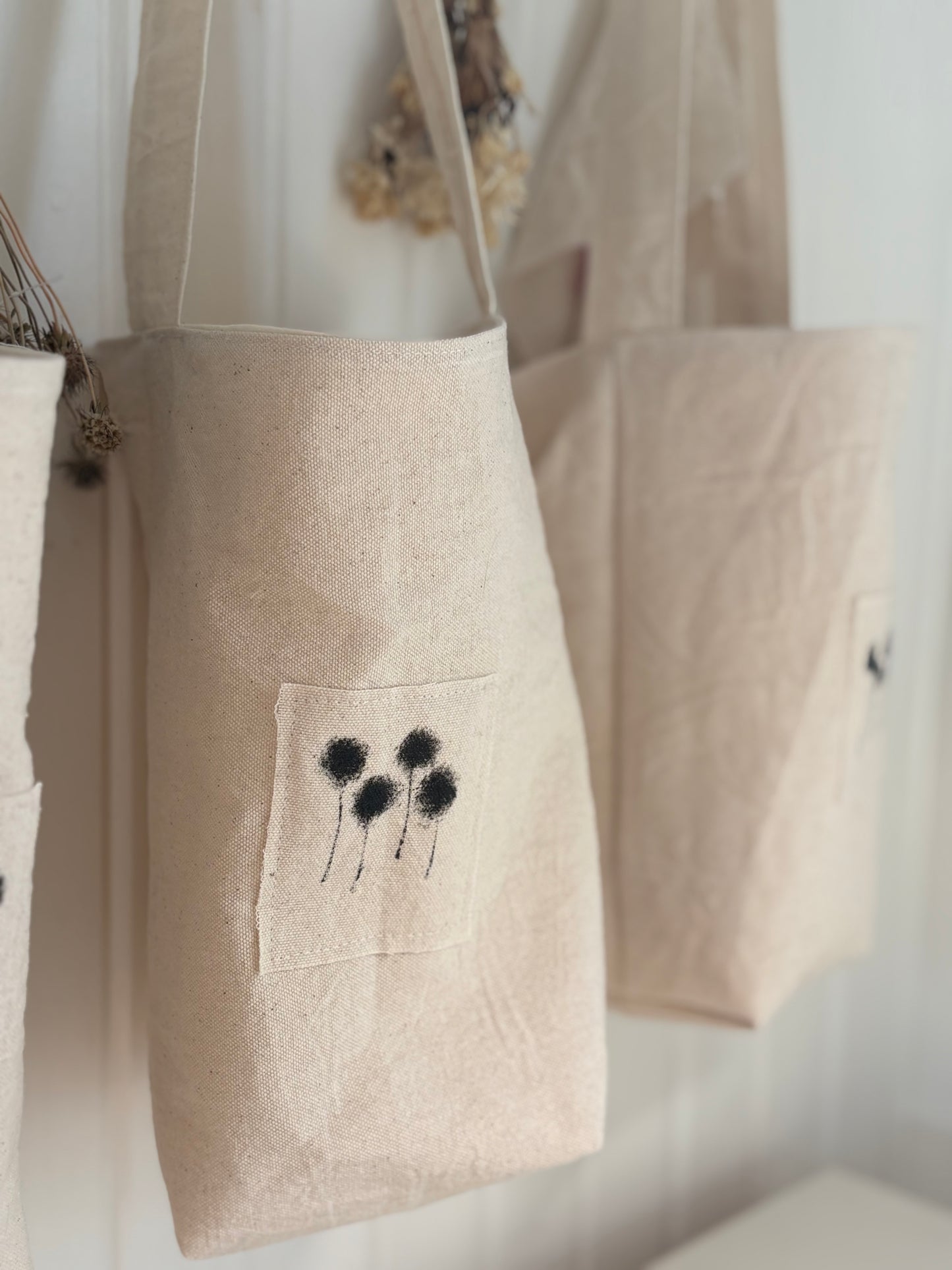 A hand painted applique of billy buttons is sewn onto the front of the posy tote