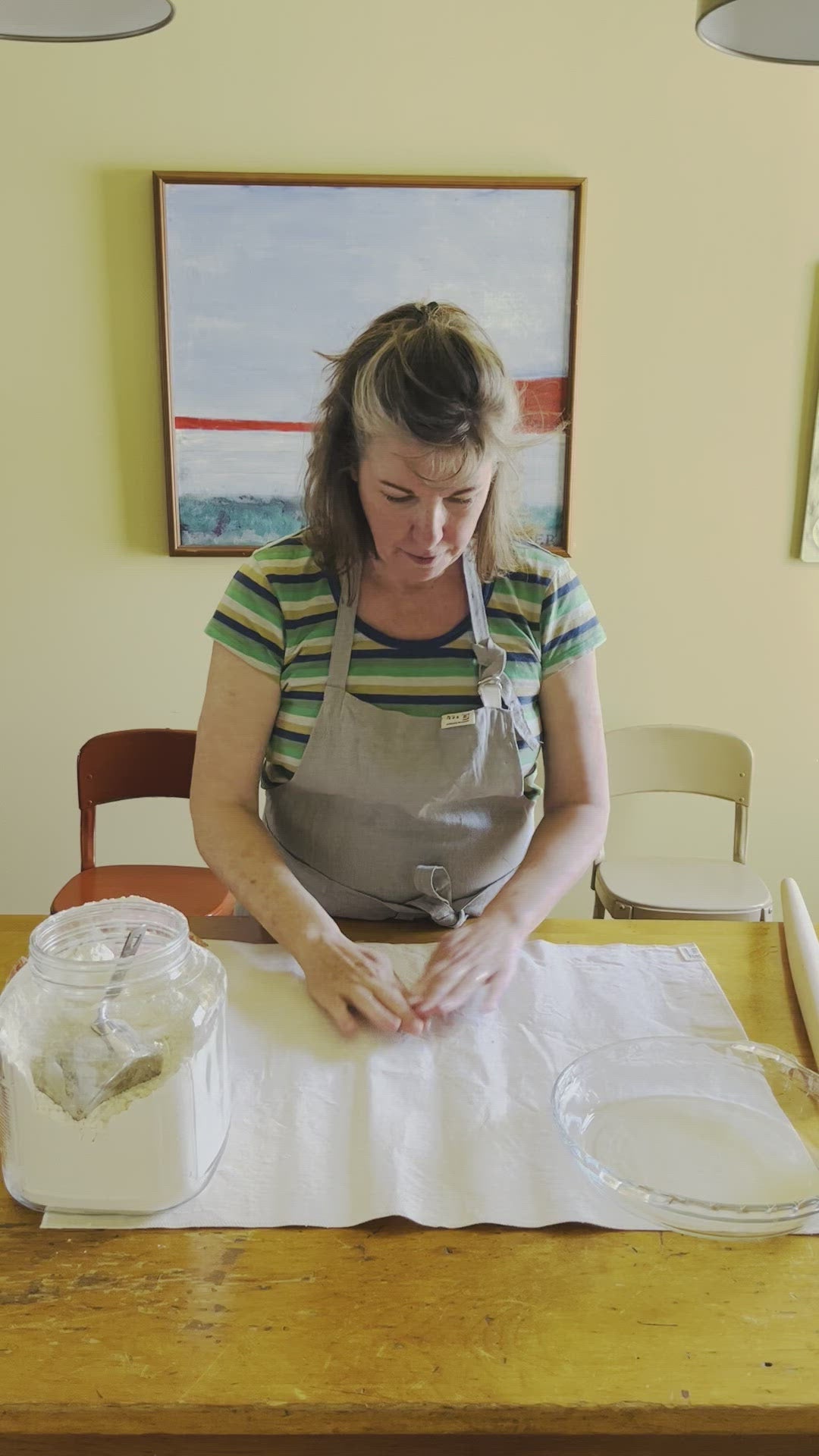 Kim conditions a pastry cloth by rubbing flour into the cloth before rolling out pie dough.