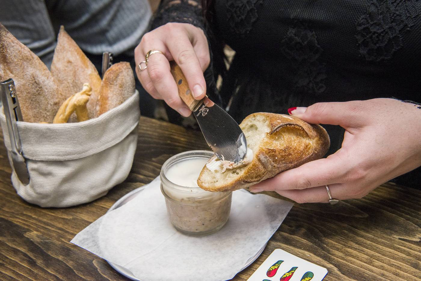 The bucket shown as a bread basket. A woman in the foreground is slathering pate on a piece of baguette