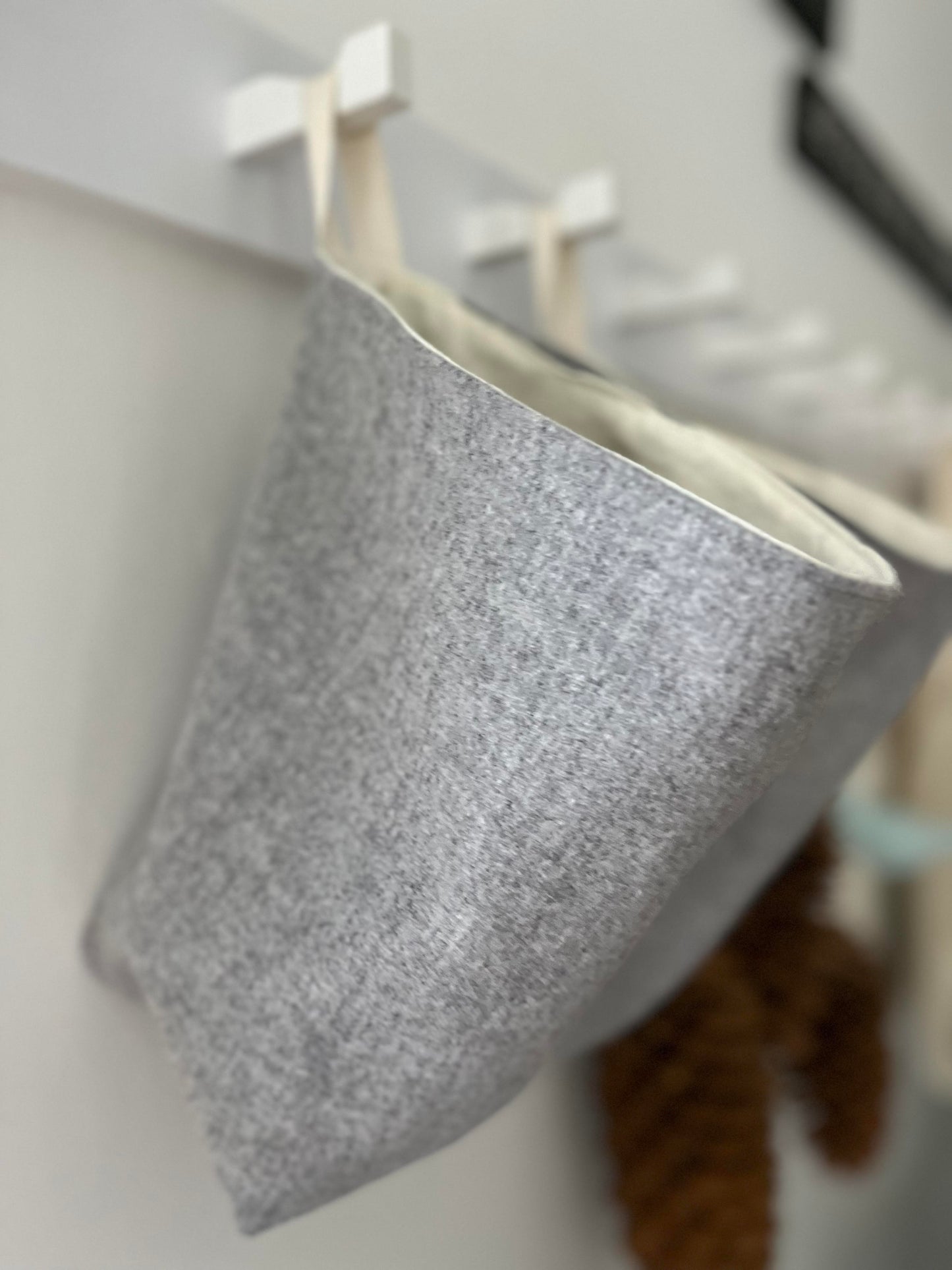 Side view of a grey wool all purpose sack lined with ivory flannelette hanging from a rail in the foyer.