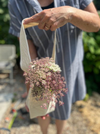 A woman holds the posy tote filled with flowers. 