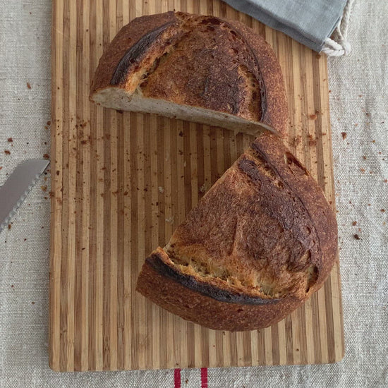 Video clip: A handmade ;oaf of bread sits on a wooden bread board cut in half. The two halves are put together then put into the hand-sewn linen bread bag. This is the best way to store your loaf keeping it fresh up to 5 days.