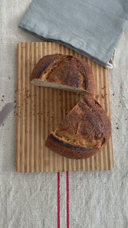 Video clip: A handmade ;oaf of bread sits on a wooden bread board cut in half. The two halves are put together then put into the hand-sewn linen bread bag. This is the best way to store your loaf keeping it fresh up to 5 days.