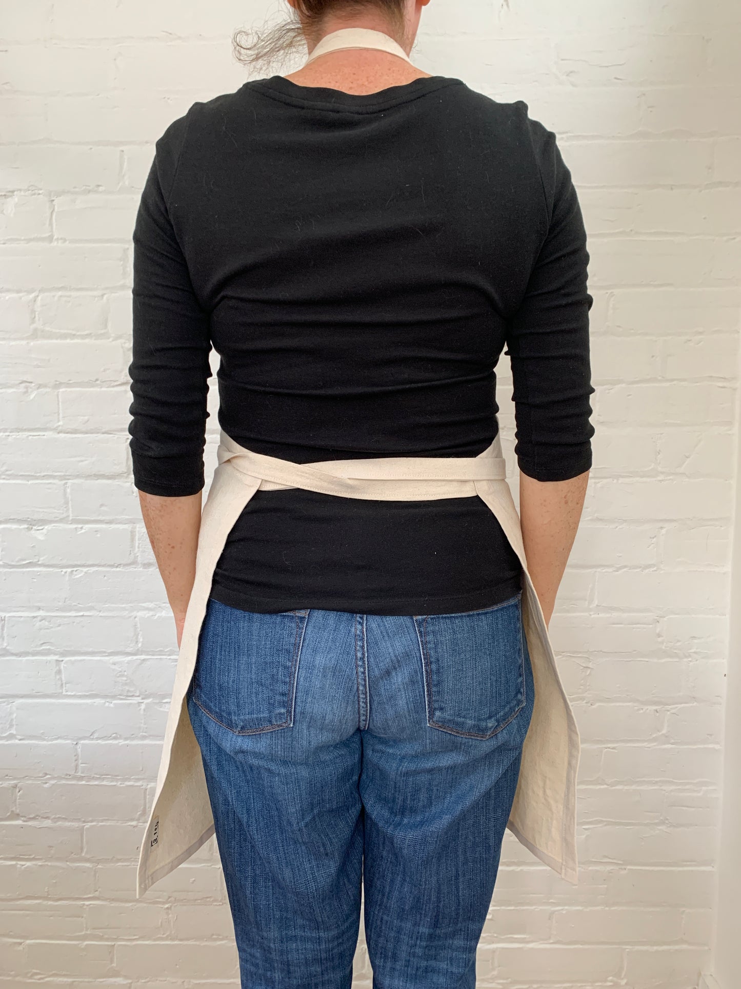 Back view of woman wearing cotton canvas apron.