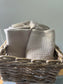 A woven basket is filled with folded face cloths.