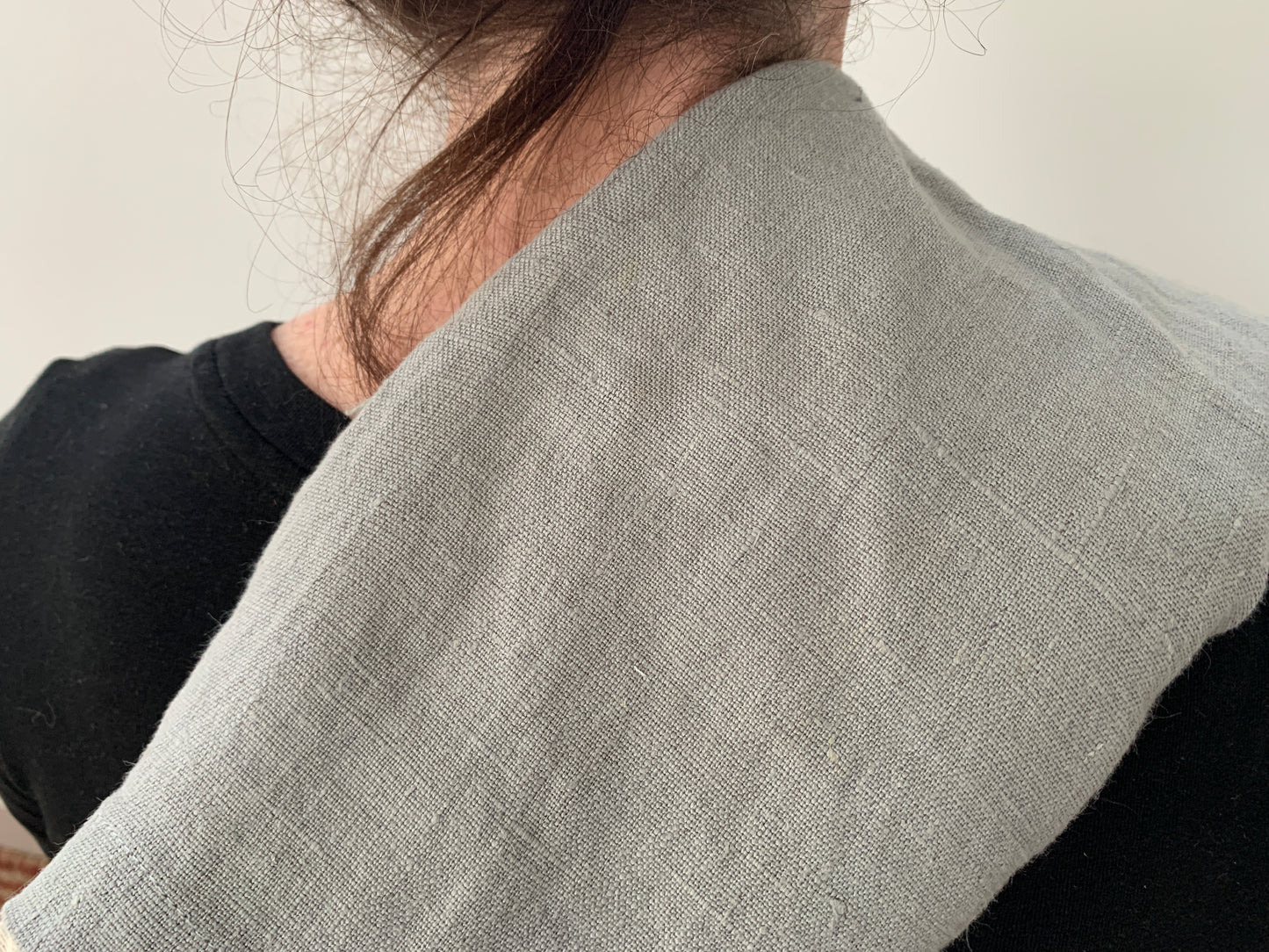 A woman stands with the therapy wrap draped over one shoulder. A tendril of hair falls along her neck.